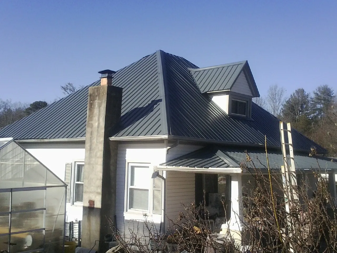 Dark blue standing seam metal roof on a white farmhouse with dormer — Slate & Tile Roof Repair by Roofing Brothers in Gower