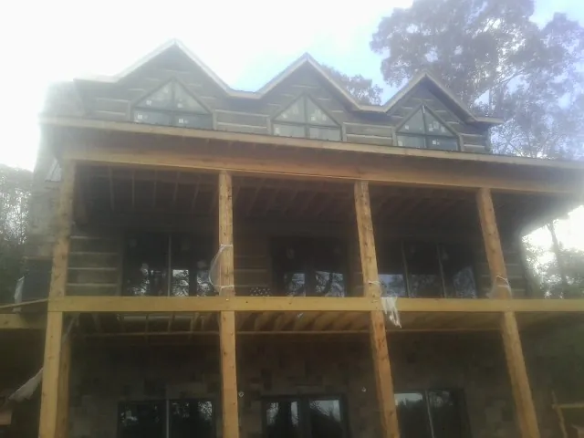 Dormers and porch framing on a large log home under construction — Roof Coating work by our crew in Gower