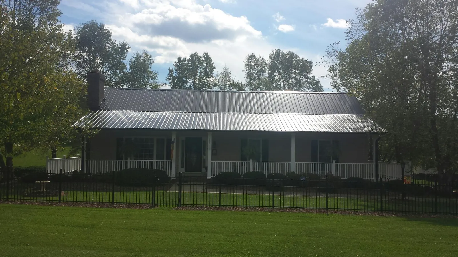 Gray metal roof on a brick ranch with a full width front porch — Gutter Guard Installation work by our crew in Gower