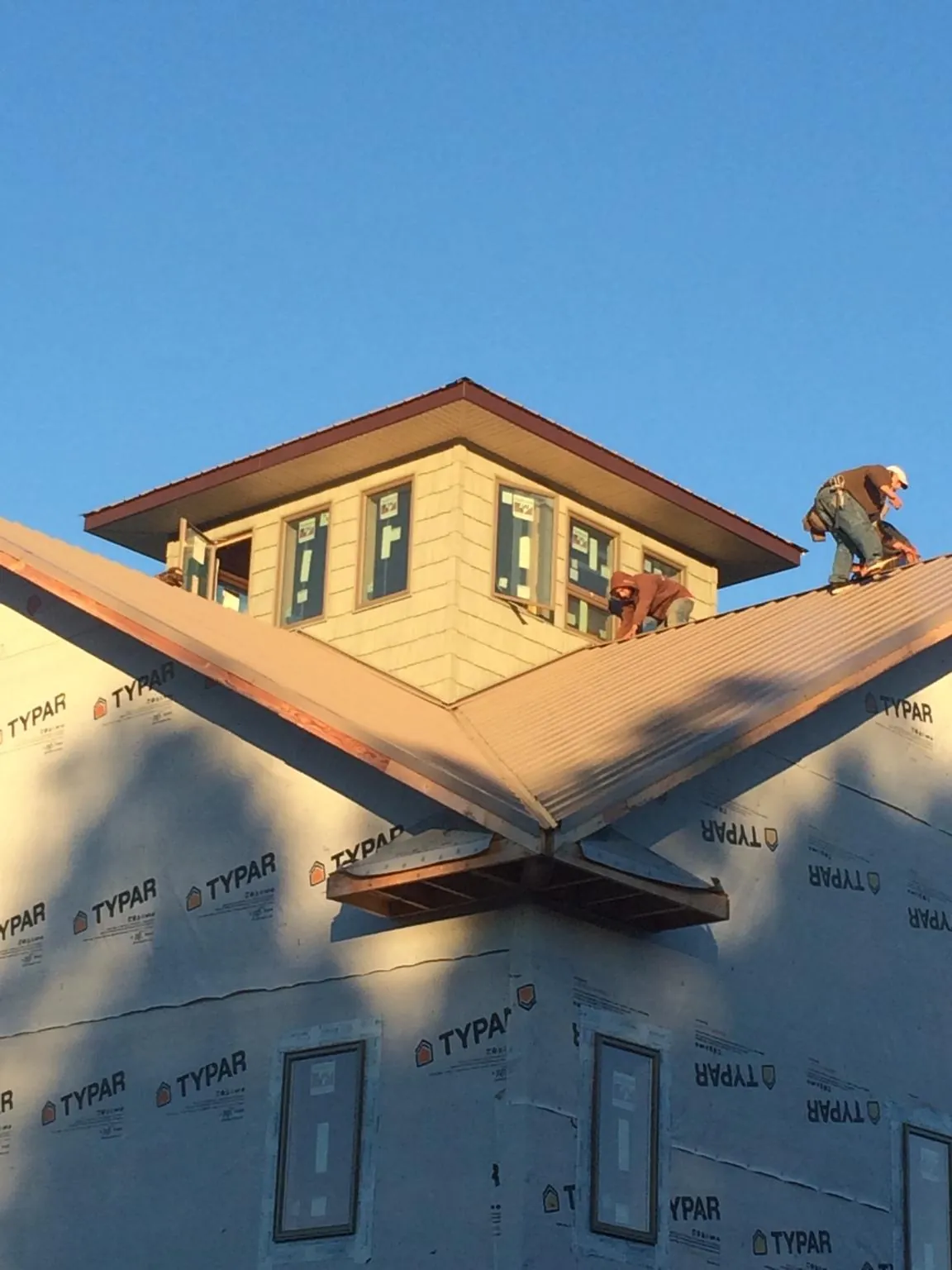 Roofers working around a rooftop cupola on a new metal roof at sunset — Roof Waterproofing in Gower by Roofing Brothers